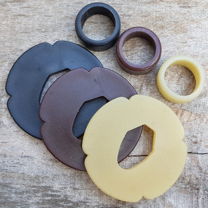 A set of plastic tsuba in black, brown, and beige colors, designed for use with wooden bokken in fencing. 