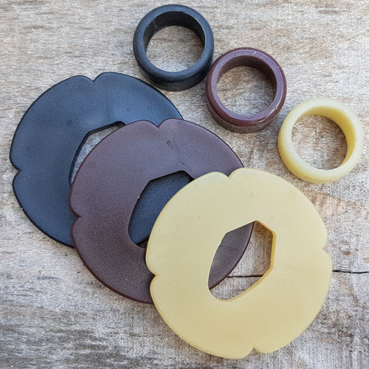 A set of plastic tsuba in black, brown, and beige colors, designed for use with wooden bokken in fencing. 