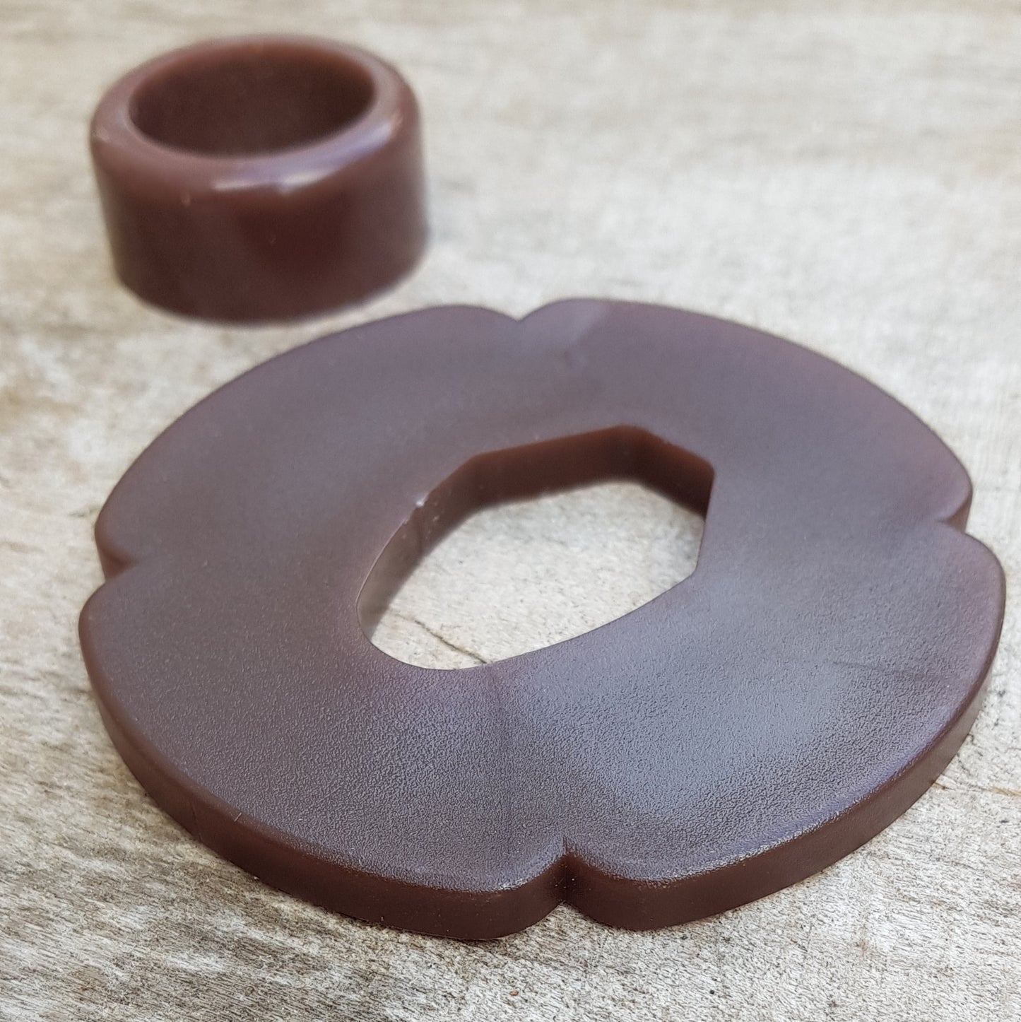 A set of plastic tsuba in black, brown, and beige colors, designed for use with wooden bokken in fencing.