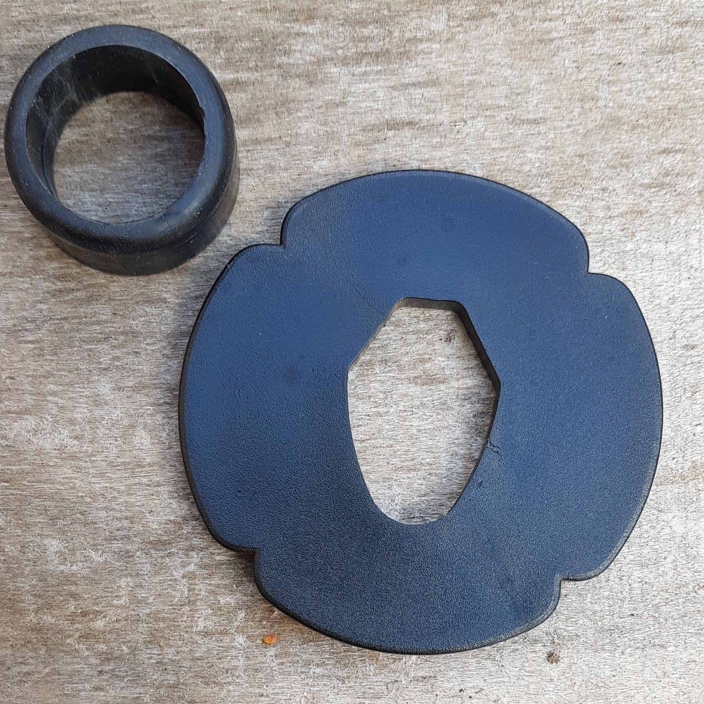 A set of plastic tsuba in black, brown, and beige colors, designed for use with wooden bokken in fencing. The tsuba are in various sizes and shapes, with a four-leaf petal form for protecting the hand.