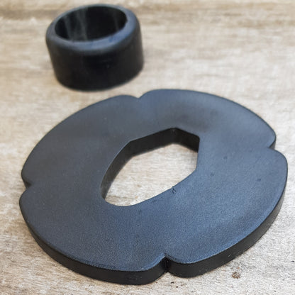 A set of plastic tsuba in black, brown, and beige colors, designed for use with wooden bokken in fencing. The tsuba are in various sizes and shapes, with a four-leaf petal form for protecting the hand.