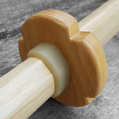 A wooden tsuba, shaped like a four-leaf petal, next to a rubber stopper, both made of European Ash wood.