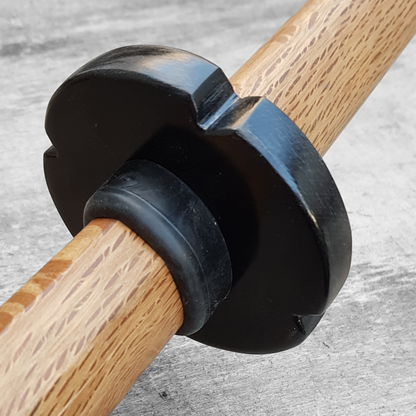 A black and brown wooden tsuba for bokken, displayed with a rubber stopper.