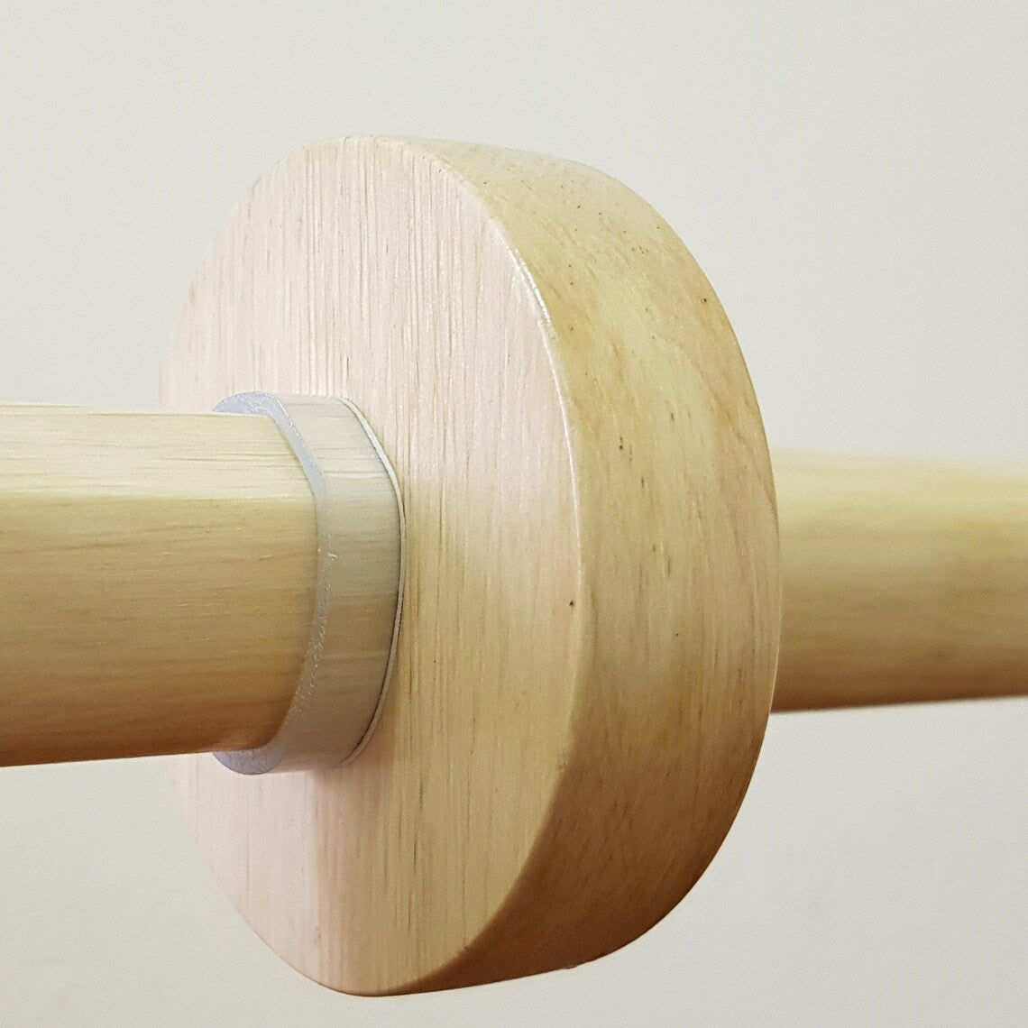 A wooden tsuba, which is a type of protective cover, placed next to a clear plastic clamp on a wooden surface.