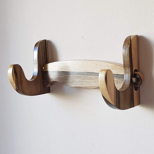 A wall mounted wooden rack designed to hold a sword, ax, or rifle, featuring a natural walnut finish.